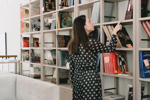 Девушка выбирает книгу на полке